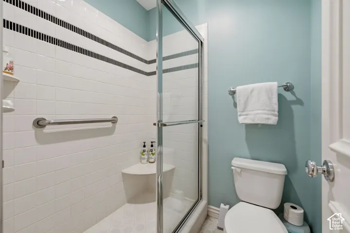 Glass-enclosed shower with a built-in bench, white tile surround, and grab bar