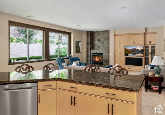 Kitchen island with a dark stone-finish countertop and light wood-finish cabinetry