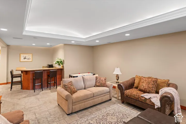 Recessed lighting, tray ceiling with cove lighting, tiled flooring, built-in wet bar, and neutral wall tones