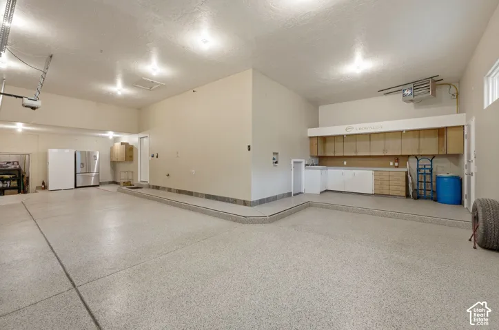 Expansive garage space with epoxy flooring, recessed lighting, built-in cabinetry, and integrated sink