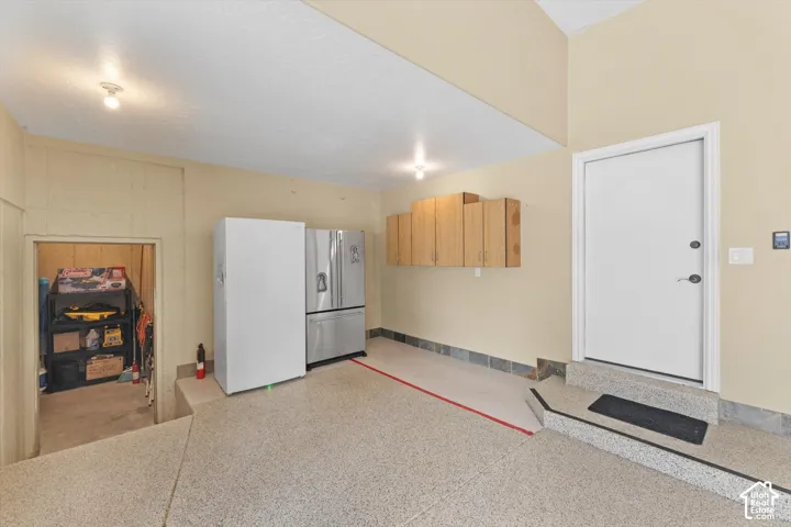 Garage featuring a speckled epoxy floor, built-in wooden cabinetry, and an interior access door