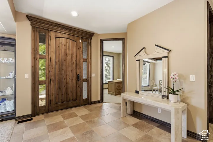 Arched solid wood front door with sidelights, detailed wood trim, and checkerboard tile flooring