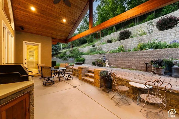 Covered outdoor patio with wood-paneled ceiling, exposed wood beams, and built-in outdoor grill station