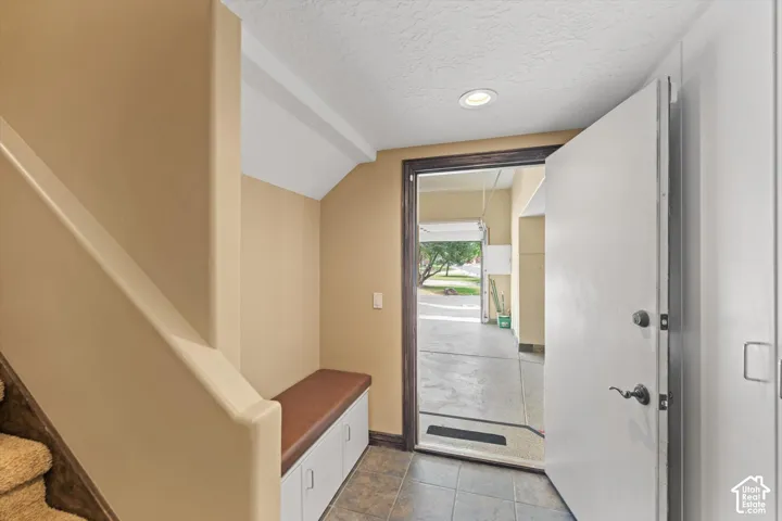 Integrated built-in bench with storage, recessed ceiling lighting, multi-tone tile flooring, and direct access to garage