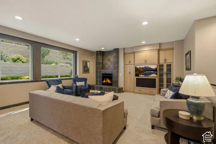 Recessed lighting, corner fireplace with tile surround, built-in media cabinetry with wood-finish doors, multiple windows, and carpeted flooring