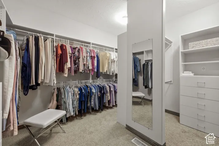 Walk-in closet featuring built-in shelving, multiple hanging rods, integrated drawer storage, and a full-length mirror