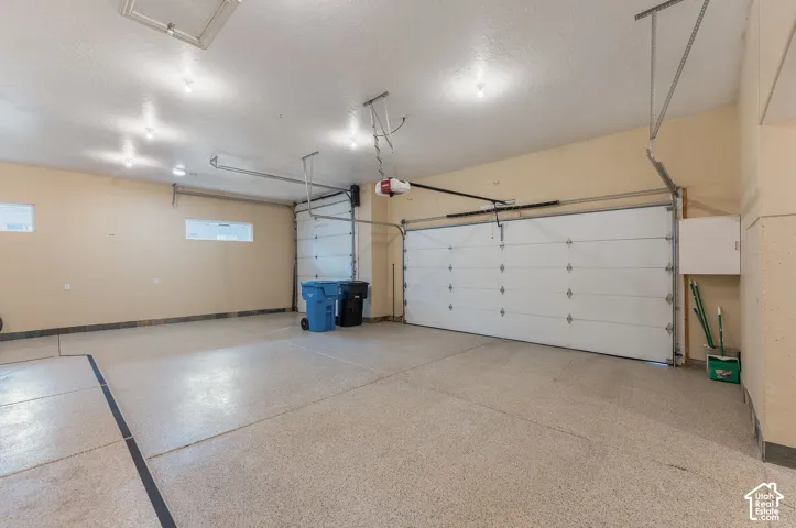 Attached two-car garage featuring epoxy flooring, two overhead garage doors, and built-in wall cabinetry