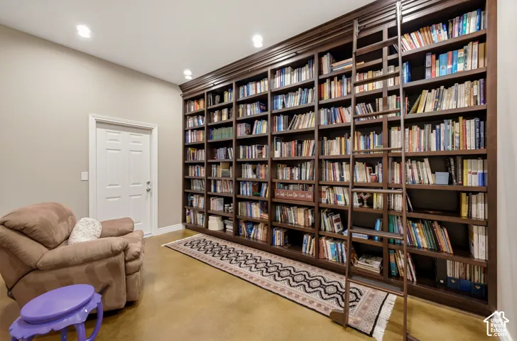 Floor-to-ceiling built-in shelving with a rolling ladder, recessed ceiling lighting, and a solid core door