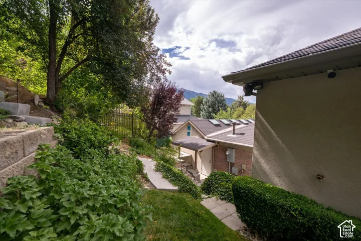 Terraced landscaping with retaining walls, established plantings, and a paved pathway