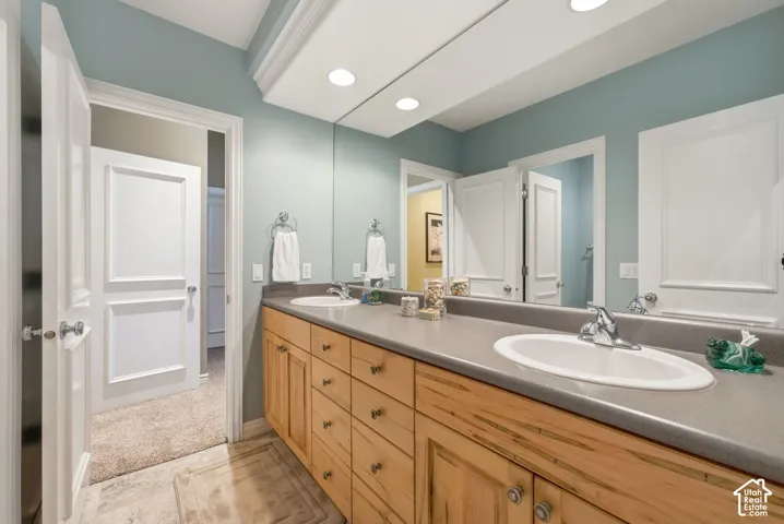 Dual vanity with integrated sinks, light wood-finish cabinetry, and a full-width mirror