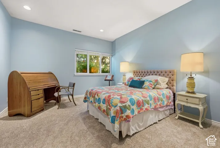 Recessed lighting illuminates the room with light blue walls and neutral-toned carpeting