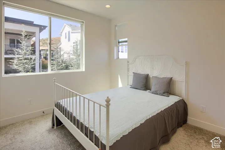 Recessed ceiling lighting, white walls, and light-colored carpeting