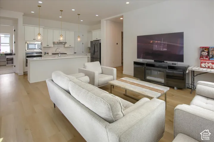 Open-concept living space featuring wood-finish flooring, recessed lighting, and a kitchen island with pendant lighting