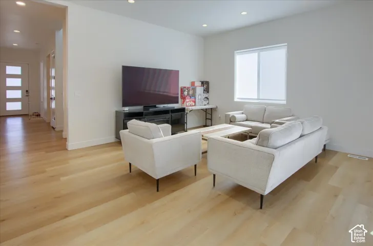 Light wood-finish flooring throughout, recessed ceiling lighting, and a front entry door with horizontal frosted glass inserts