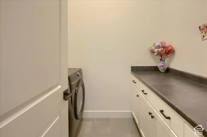 White shaker-style cabinetry with dark pulls, dark countertop, and tiled flooring