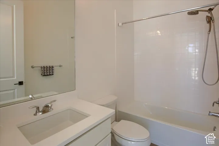White vanity with integrated sink, chrome faucet, wall-mounted mirror, white ceramic tile shower surround, and a tub/shower combination