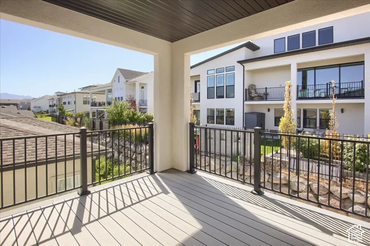 Covered balcony with composite decking, black metal railings, and a slatted ceiling