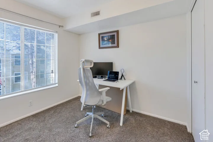 Carpeted room featuring a window with blinds, white walls, and a white door with a silver knob