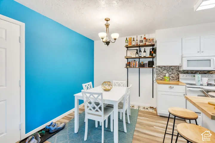 Dining area with wood-finish flooring, white door, and a bright accent wall