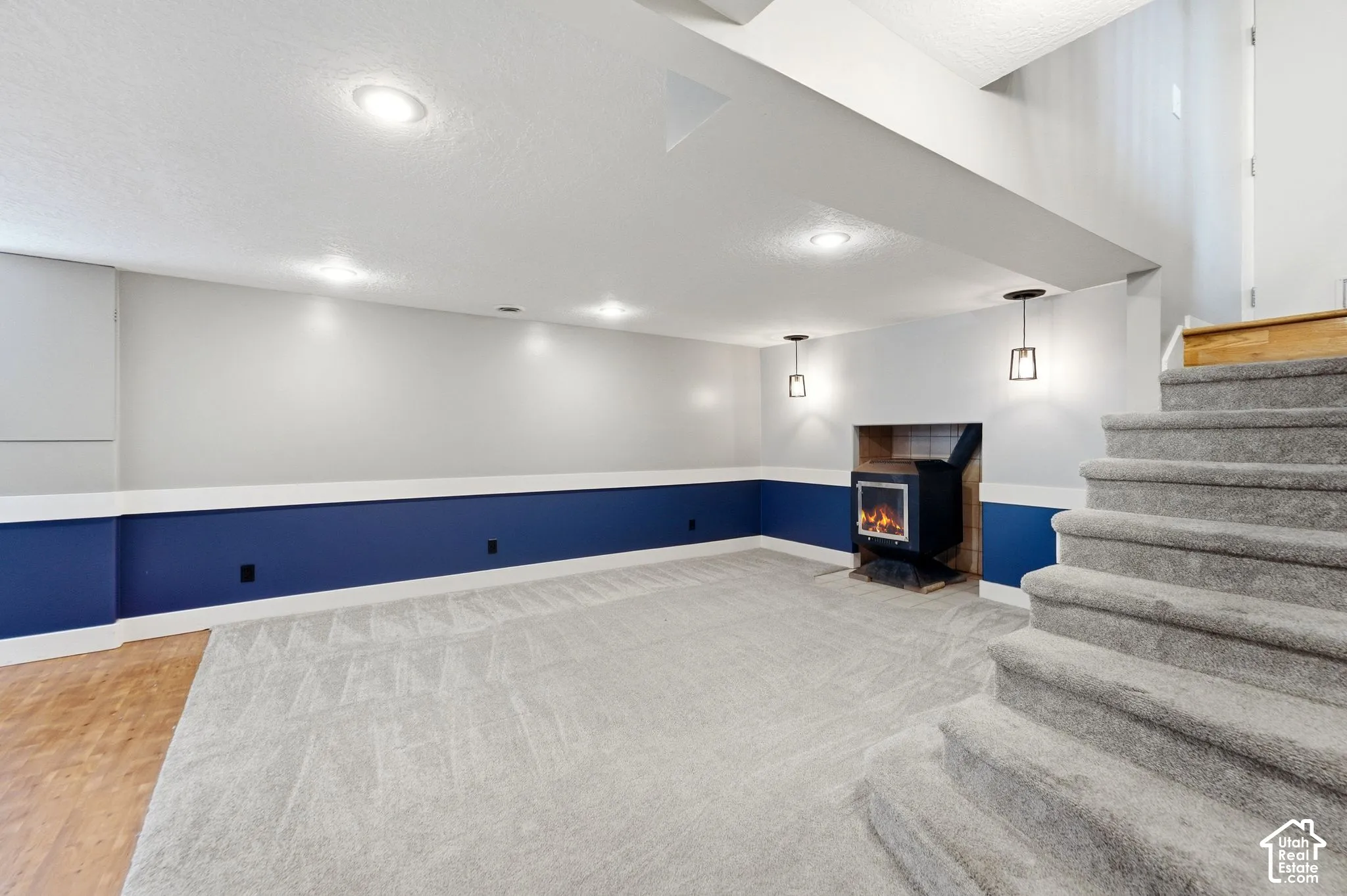 Recessed lighting, wood-finish flooring, two-tone wall treatment, built-in fireplace, and carpeted stairs