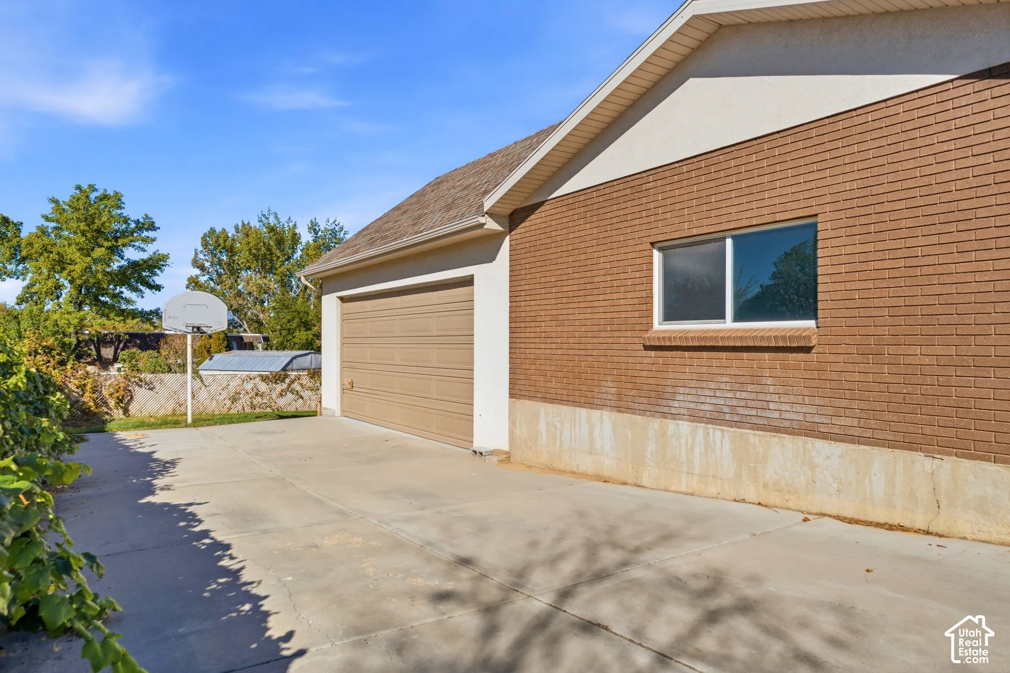 Attached garage with a tan overhead door, brick exterior, and a concrete driveway