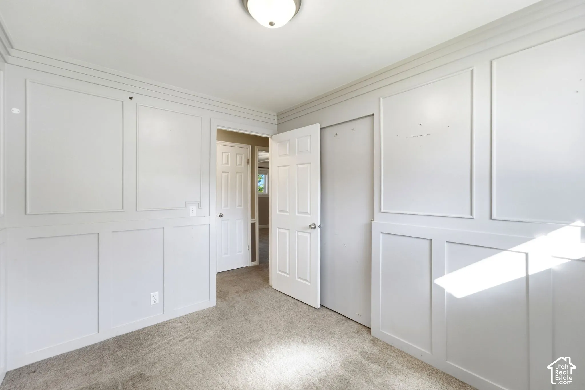 Panel-style wall trim, neutral-tone carpeting, flush mount ceiling light, and interior paneled doors