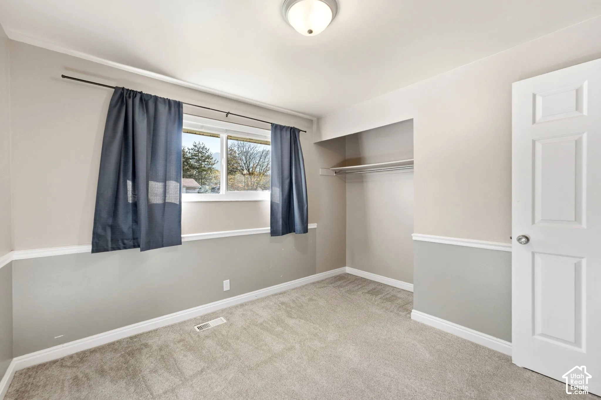 Room featuring carpet flooring, a window with exterior visibility, a built-in closet with shelving and hanging rod, and a paneled door