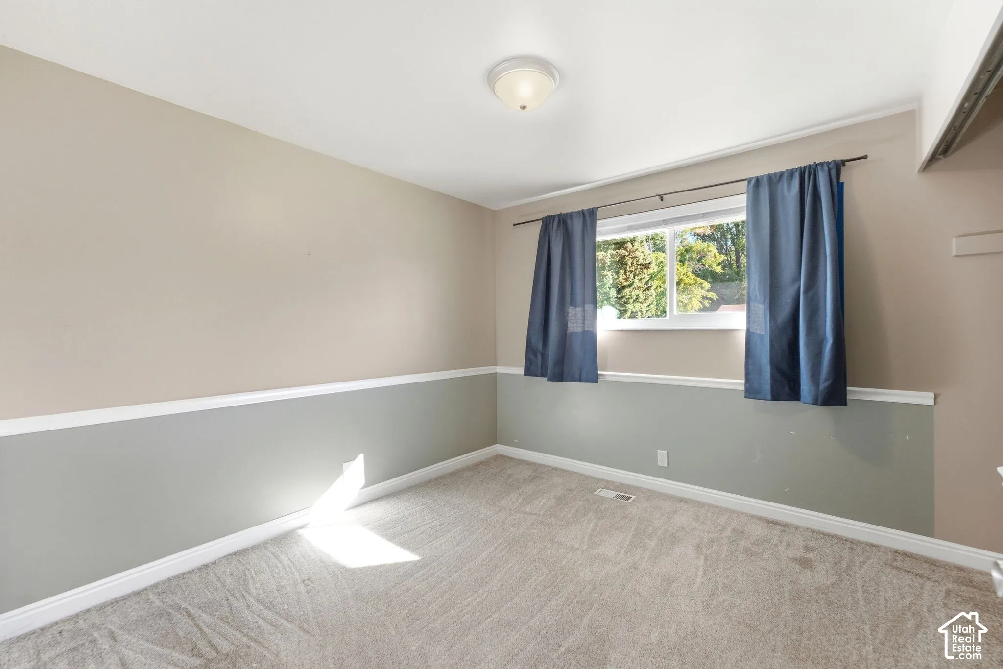 Carpeted room featuring a two-tone wall treatment, white trim, and a window