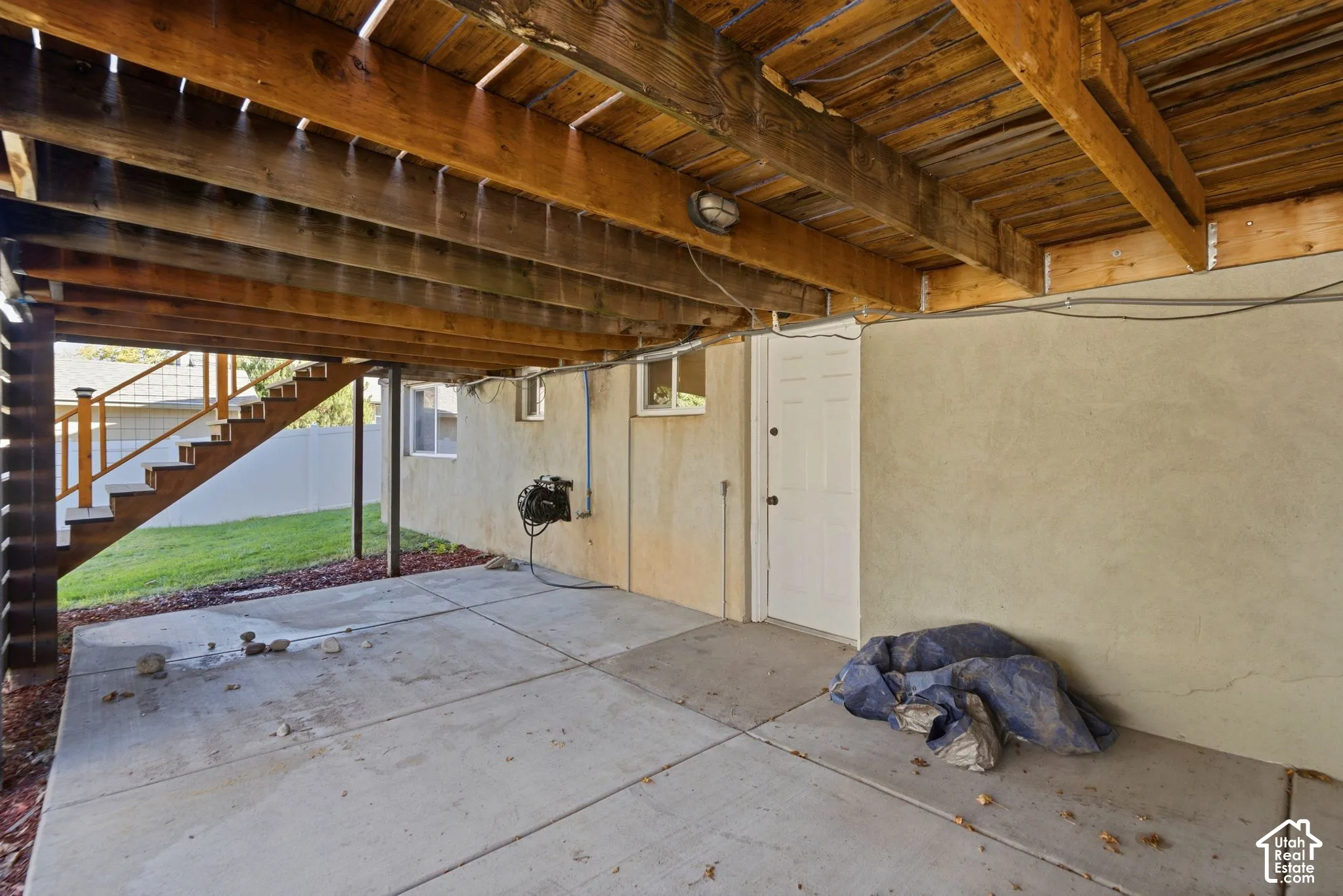 Under-deck patio with concrete slab flooring and exposed wood beam ceiling