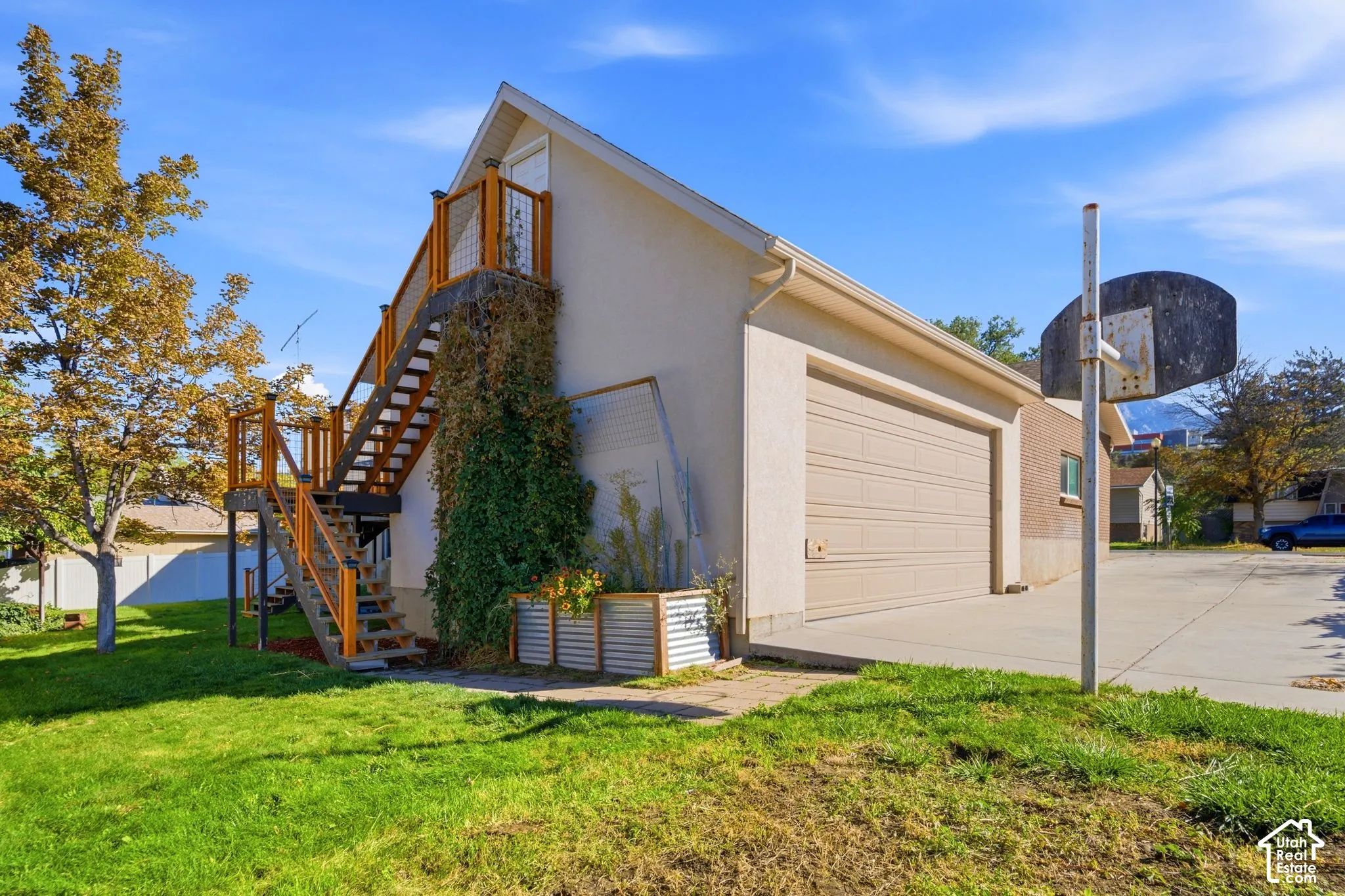 Attached two-car garage with a concrete driveway, exterior staircase with wood railings, and an expansive lawn