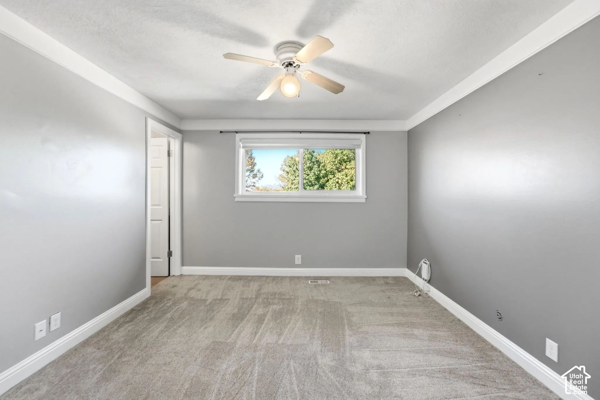 Spacious bedroom with neutral gray walls, wood-finish flooring, and recessed lighting throughout
