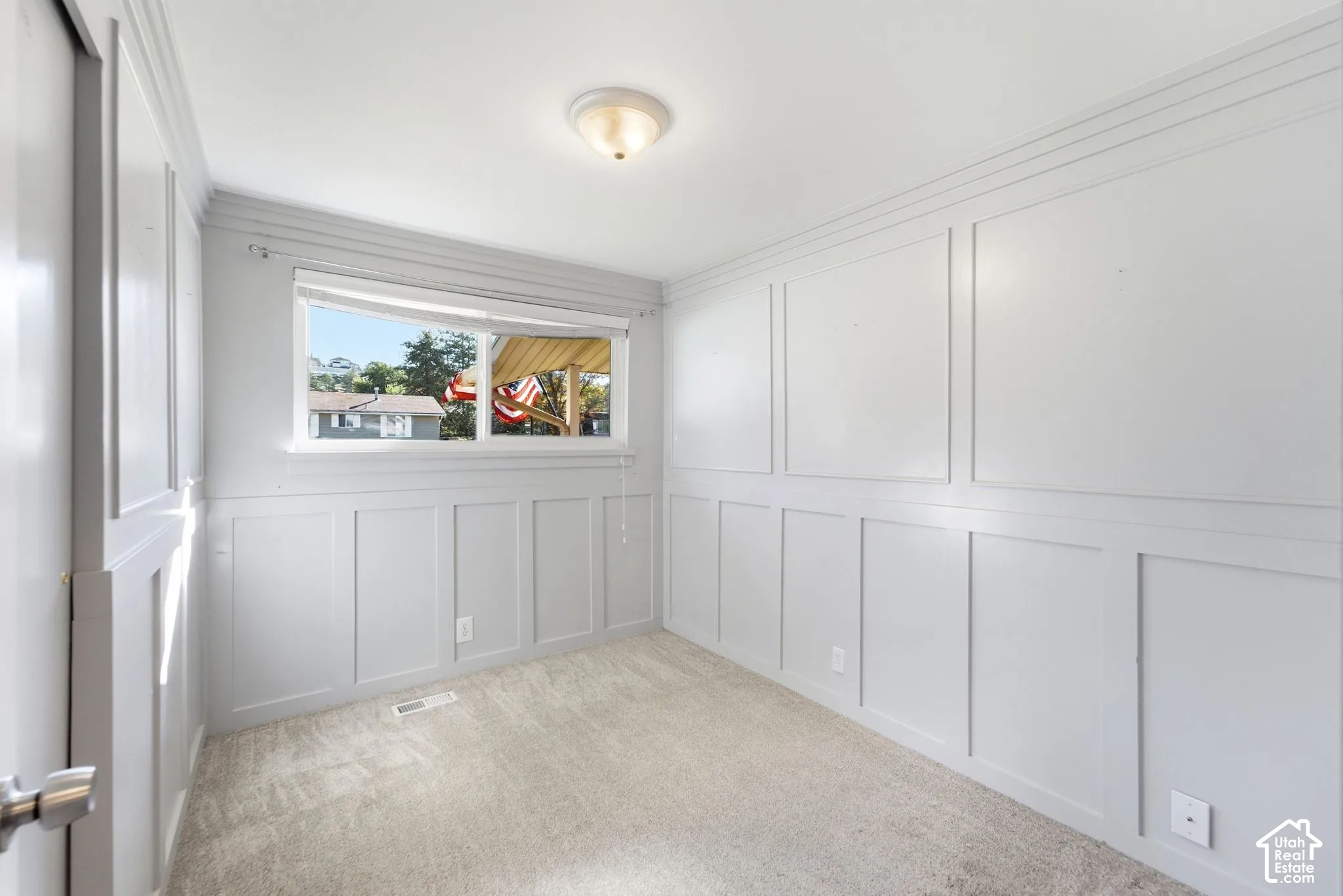 Board and batten wall detailing, crown molding, flush mount ceiling light, window, and carpeted flooring
