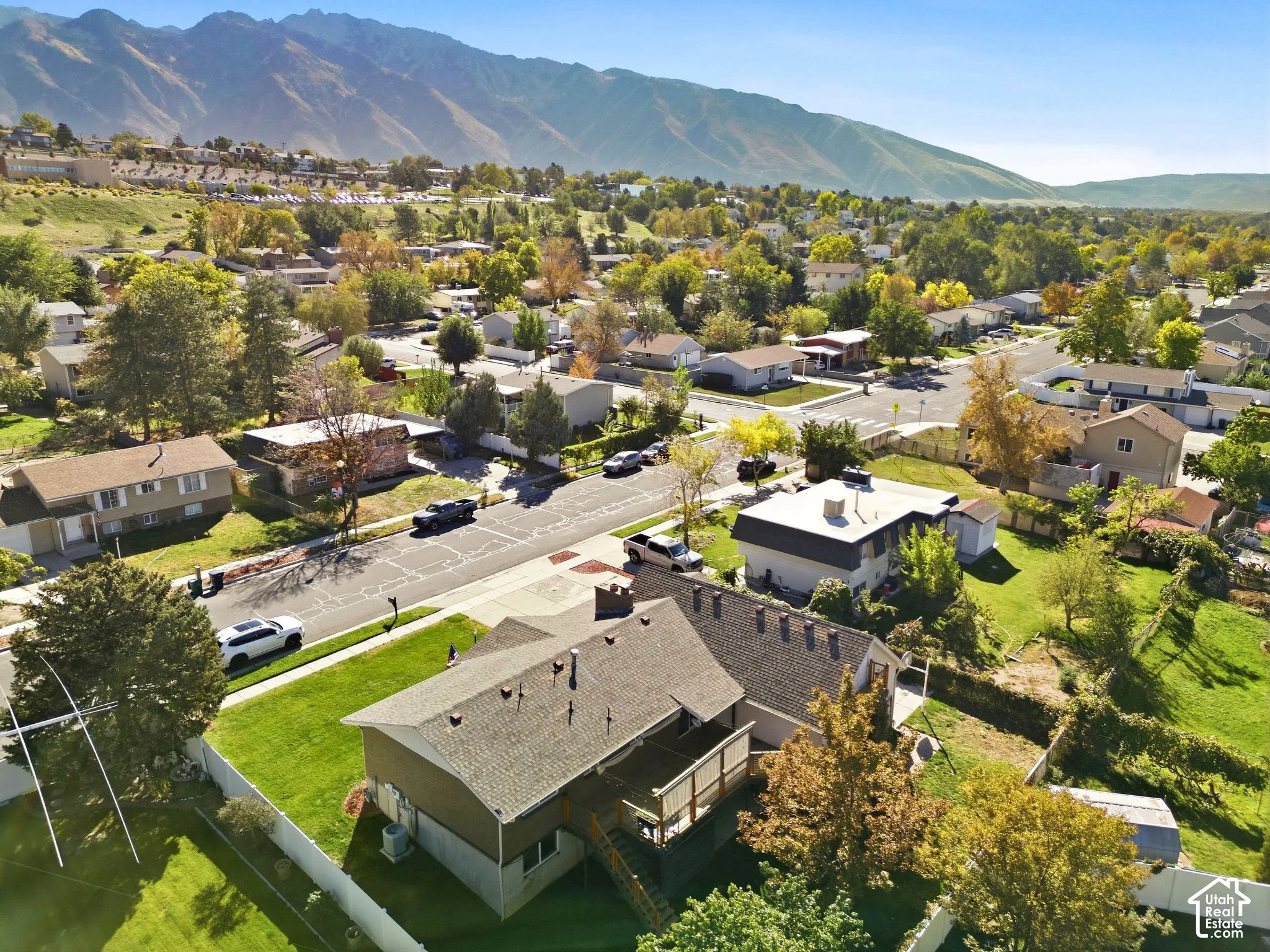 Expansive lot with lush green lawn, mature trees, and a multi-level deck
