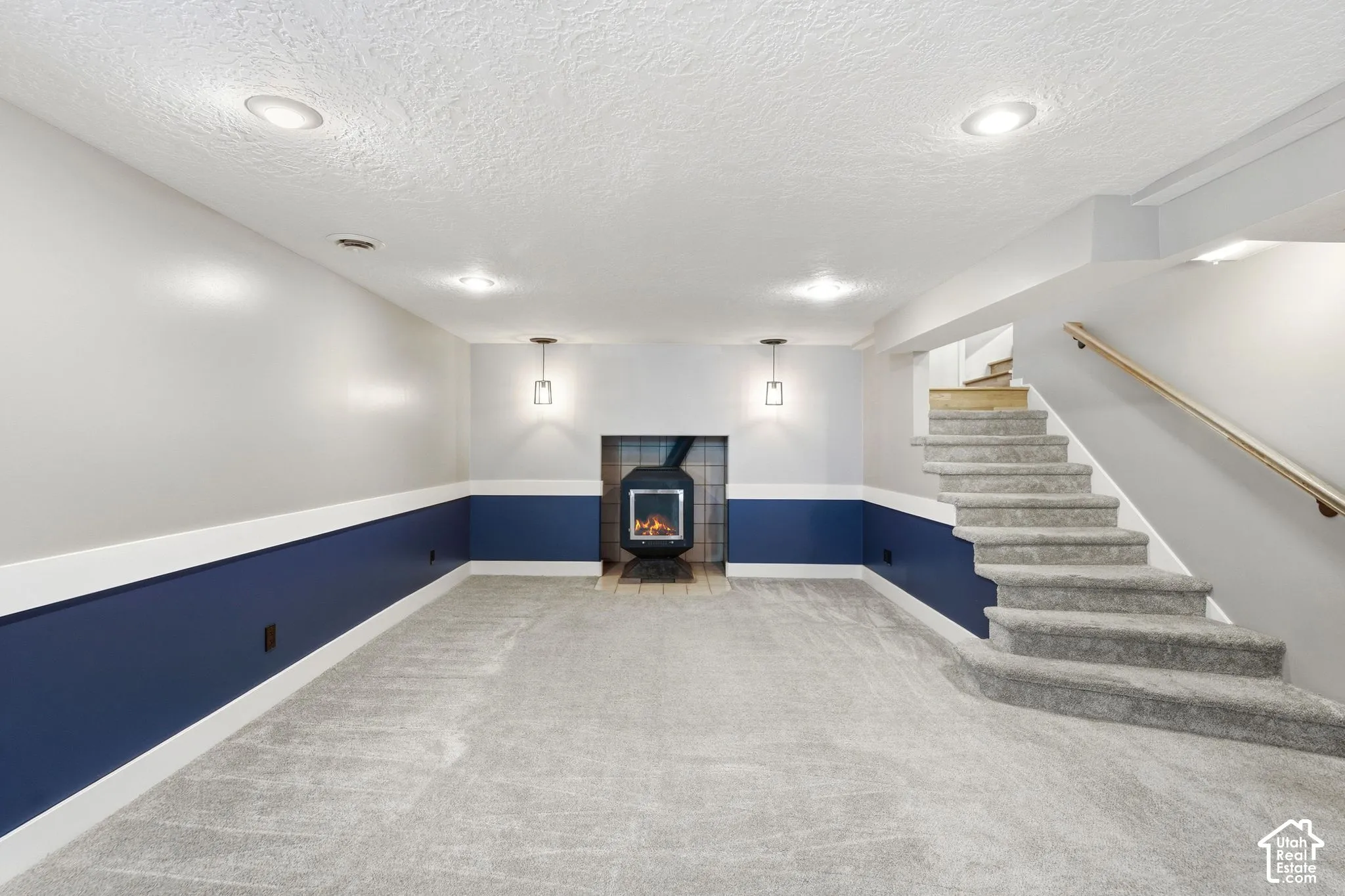 Carpeted flooring, recessed lighting, wall-mounted light fixtures, built-in fireplace, and a staircase with a wood handrail