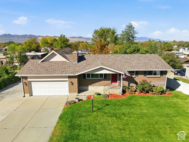 Brick exterior with a peaked roofline, attached garage, and a manicured lawn