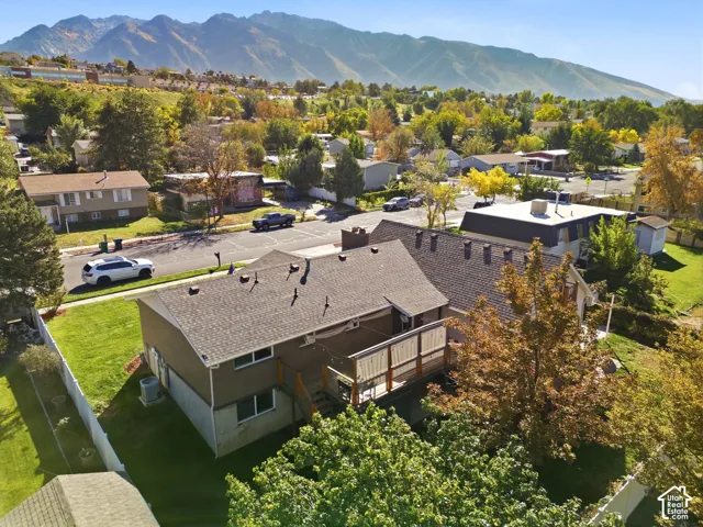 Property exterior with a multi-level deck, fenced yard, and surrounding mature trees
