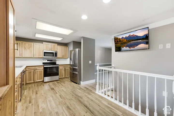 Kitchen featuring wood cabinetry, stainless steel appliances, white countertops, and wood-finish flooring