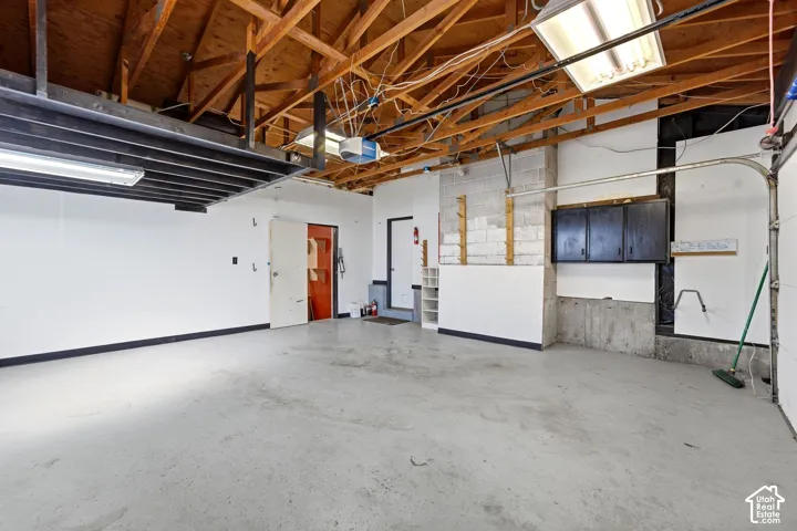 Exposed wood beam ceiling, concrete flooring, overhead storage, storage cabinetry, and built-in shelving