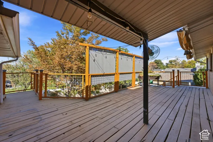 Expansive wood deck with a partial overhead covering, wood and wire railing, and privacy screening