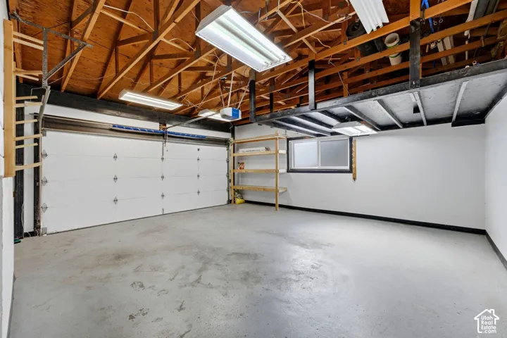 Concrete flooring, exposed wood beam ceiling, white walls, built-in shelving, and frosted window