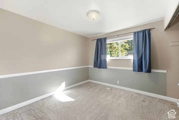 Carpeted room featuring a two-tone wall treatment, white trim, and a window