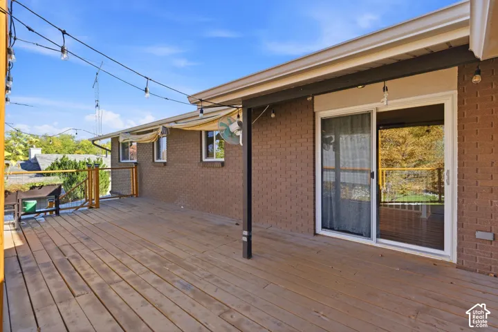 Expansive outdoor deck with wood-finish flooring, brick exterior, and white-framed sliding glass door