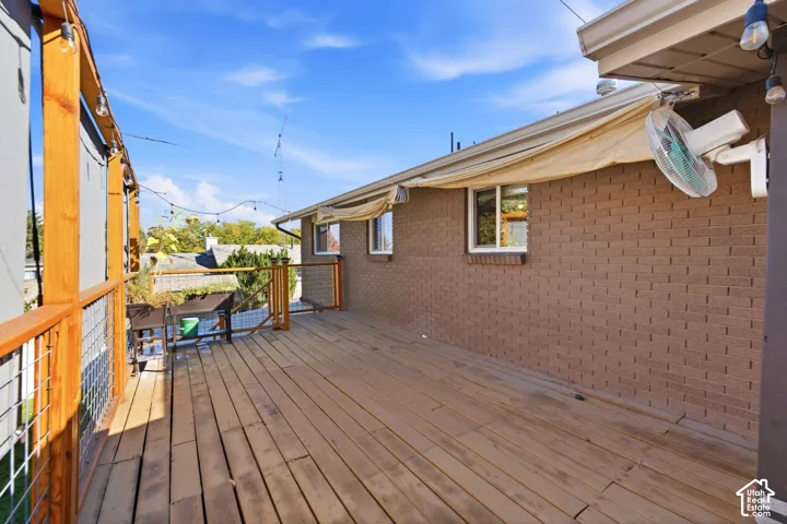 Expansive composite deck featuring wood-finish flooring and multiple outdoor living zones, with brick exterior and covered overhang providing shelter