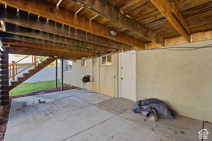 Under-deck patio with concrete slab flooring and exposed wood beam ceiling