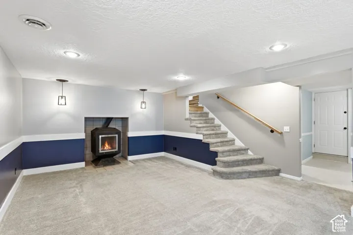 Spacious room featuring a wood-burning stove, recessed lighting, wall sconces, and carpeted flooring