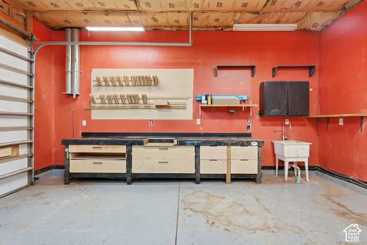 Dedicated workshop space featuring vibrant red walls, concrete flooring, and ample built-in storage with wood-finish cabinetry and open shelving