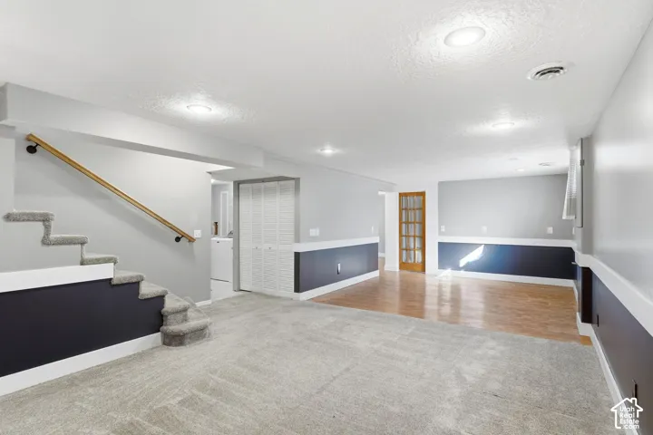 Spacious room featuring carpeting, wood-finish flooring, recessed lighting, and a paneled door with glass inserts