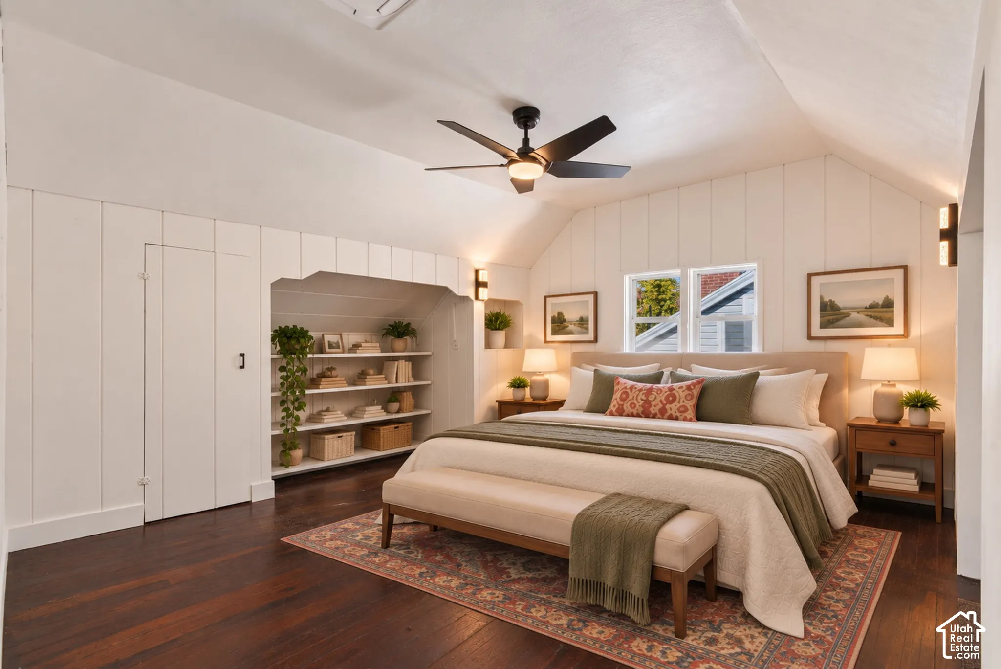 Vaulted ceiling, wood-finish flooring, built-in shelving, white paneled walls, and a ceiling fan