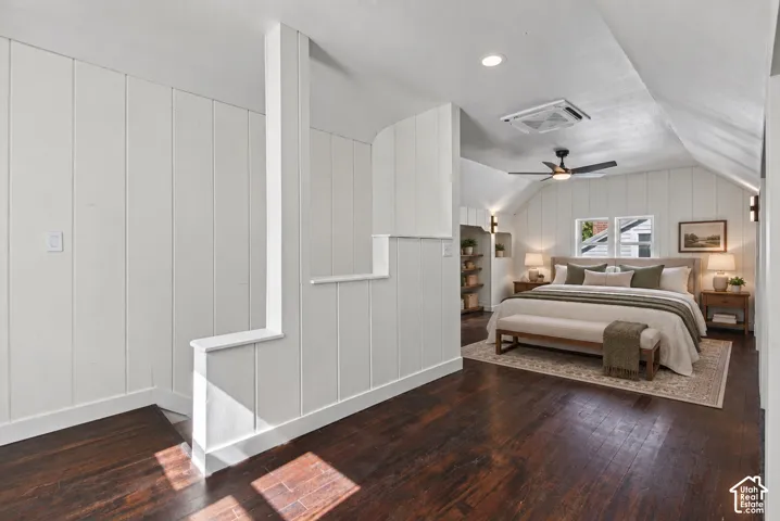 Dark wood-finish flooring with white board and batten wall paneling, vaulted ceiling, recessed lighting, and a ceiling fan