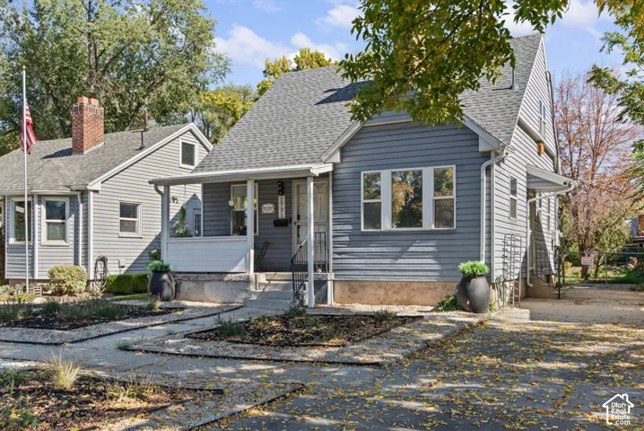 Exterior featuring gray siding, a covered front porch, and a gabled roofline